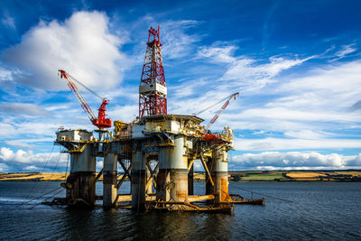 Crane by sea against sky