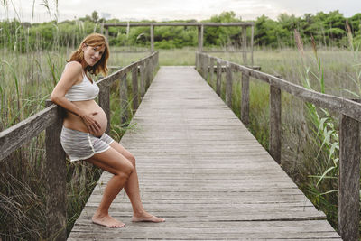 Portrait of pregnant woman standing on footpath