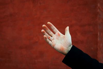 Close-up of hand against red wall