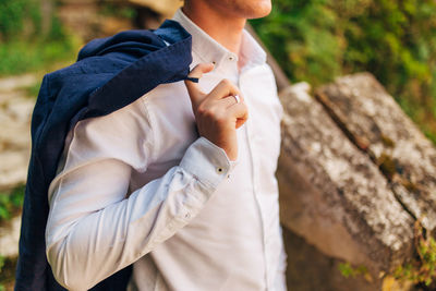 Midsection of man holding jacket outdoors