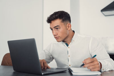 Young man using laptop while sitting on table