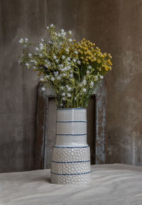 Flower vase on table against wall