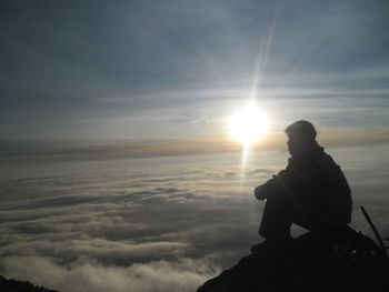 Silhouette man sitting against sky during sunset