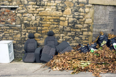 Abandoned chairs by garbage against old wall