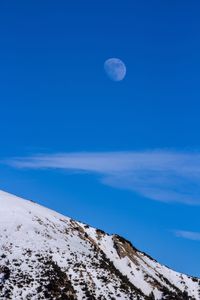 Scenic view of snowcapped mountains against blue sky