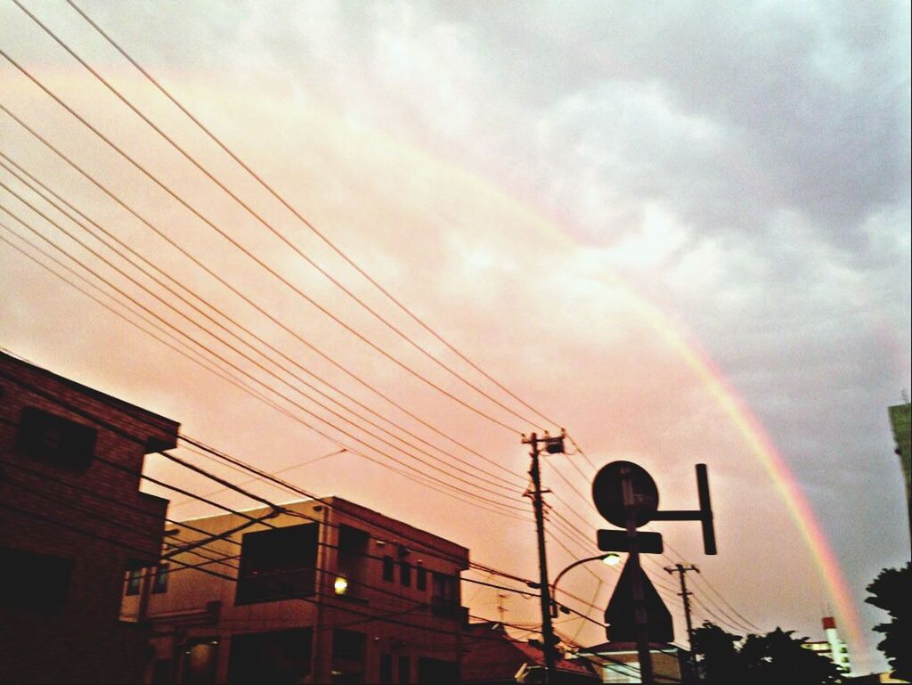 low angle view, power line, sky, electricity, cable, electricity pylon, building exterior, built structure, power supply, architecture, cloud - sky, sunset, fuel and power generation, silhouette, technology, street light, connection, lighting equipment, cloudy, communication