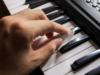 Close-up of hand cleaning piano