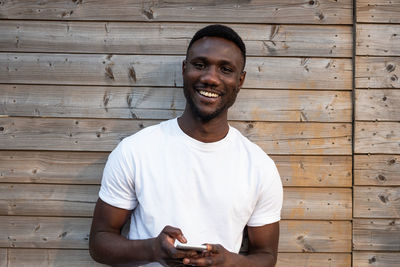 Portrait of young man standing against wooden wall