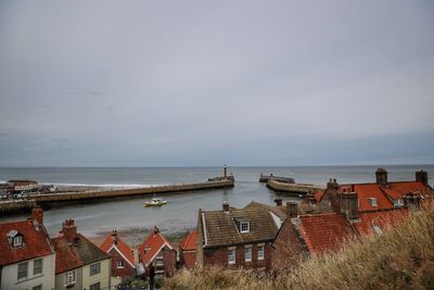 Houses by sea against sky