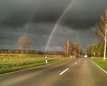 Empty country road against cloudy sky