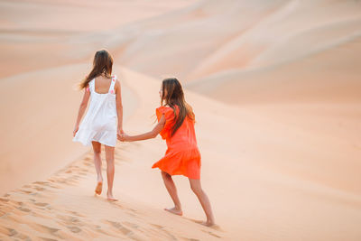 Rear view of women walking on sand dune