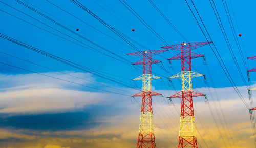 Low angle view of electricity pylon against blue sky