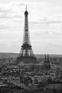 Communications tower in city against sky