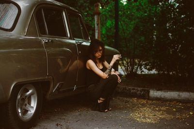 Full length portrait of woman sitting in car