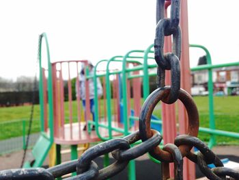 Close-up of chain swing against sky