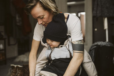 Mother dressing daughter at home