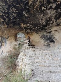 Rear view of woman sitting on rock