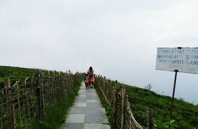 Rear view of woman with child walking on footpath at mountain
