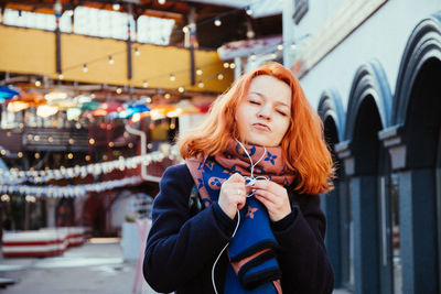 Woman with eyes closed standing against building