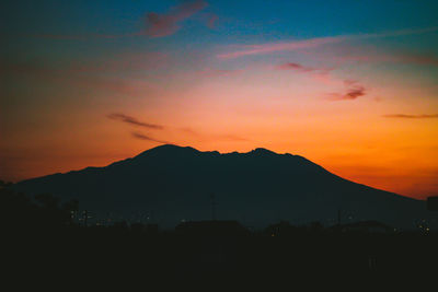 Scenic view of silhouette mountains against orange sky