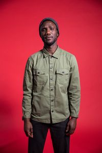 Portrait of young man standing against red background