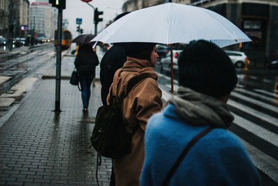 Rear view of people walking on wet street