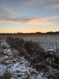 Scenic view of frozen lake against sky during sunset