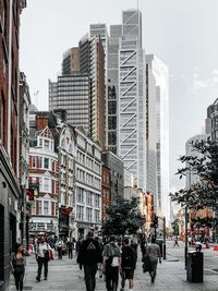 People on city street by buildings against sky