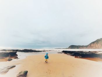 Rear view of man on beach against sky