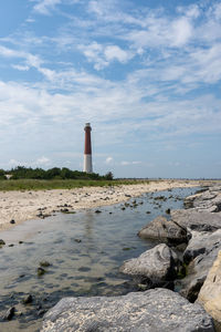 Lighthouse by sea against sky