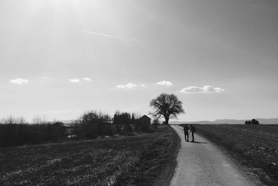 Rear view of people walking on road against sky