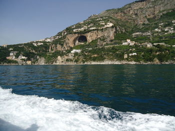 Scenic view of sea by mountain against sky