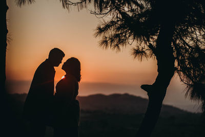 Silhouette man standing by tree against sky during sunset