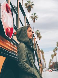 Portrait of young woman in city against sky