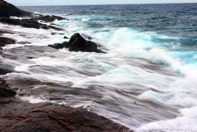 Scenic view of waves in sea against sky