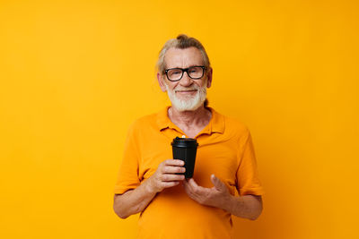 Young woman holding trophy against yellow background