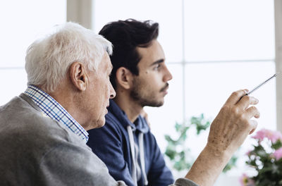 Senior man holding pen while discussing with caretaker at nursing home