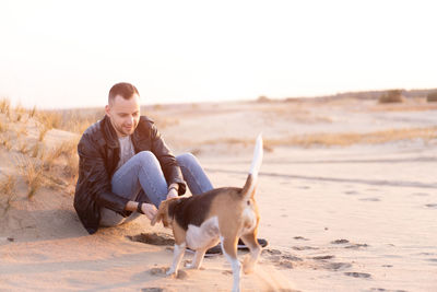 Man with dog on beach against sky