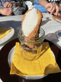 Close-up of hand with ice cream in glass on table