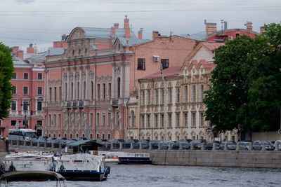 Sailboats in river by buildings in city against sky