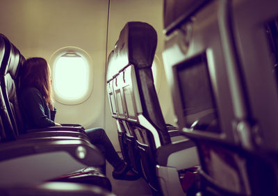 Side view of woman traveling in airplane sitting by window