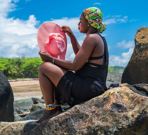 Rear view of woman sitting on rock