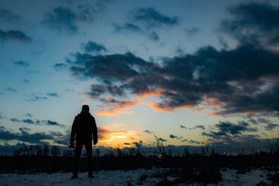 Rear view of man standing against sky during sunset