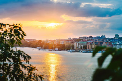 City by sea against sky during sunset