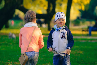 Siblings standing on field at park