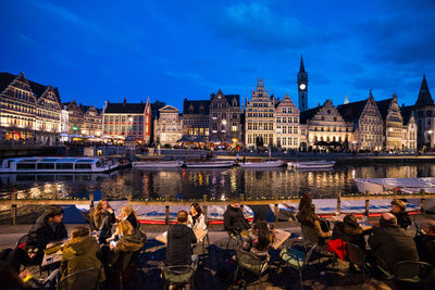 People at illuminated city against sky at night