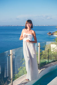 Woman standing by sea against sky