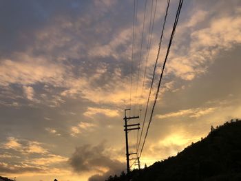 Low angle view of silhouette electricity pylon against sky during sunset