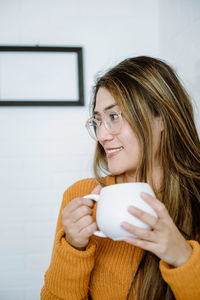 Portrait of smiling young woman drinking coffee at home