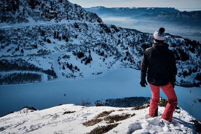 Rear view of man standing on cliff against mountains